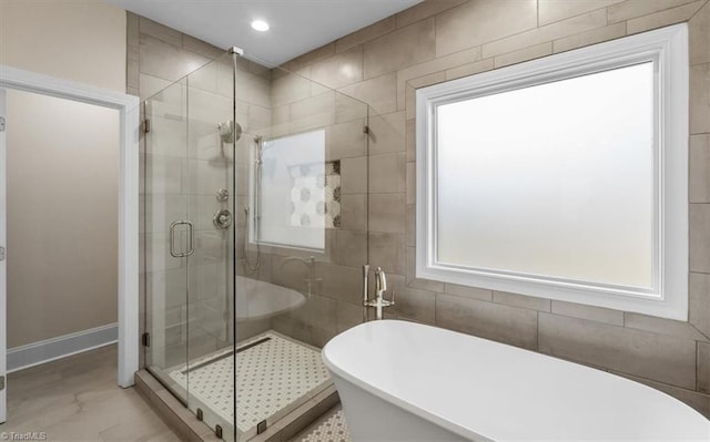 bathroom featuring recessed lighting, a stall shower, a freestanding bath, and baseboards