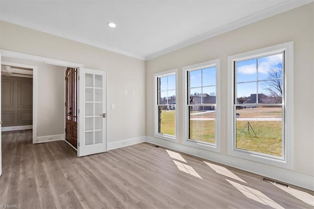 unfurnished room with visible vents, light wood-style flooring, crown molding, and baseboards