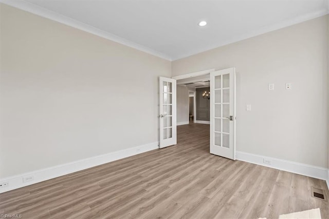 spare room with light wood finished floors, visible vents, baseboards, ornamental molding, and french doors