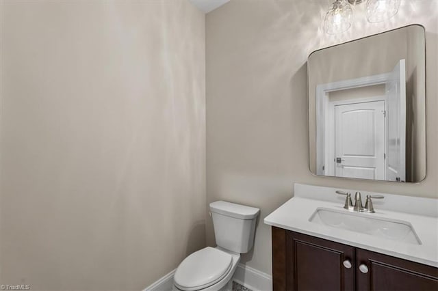 bathroom featuring toilet, vanity, and baseboards