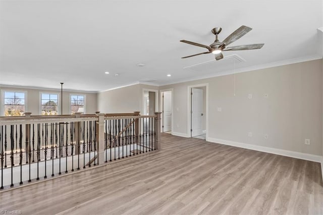 unfurnished room featuring wood finished floors, recessed lighting, crown molding, baseboards, and attic access