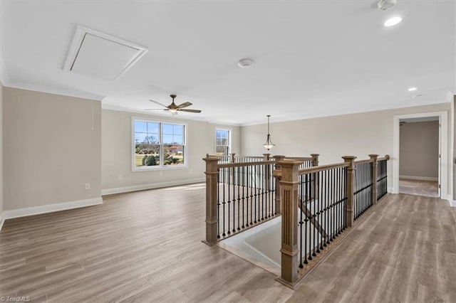 hall featuring baseboards, attic access, ornamental molding, an upstairs landing, and light wood-type flooring