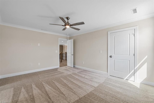 empty room featuring visible vents, ornamental molding, baseboards, light colored carpet, and ceiling fan