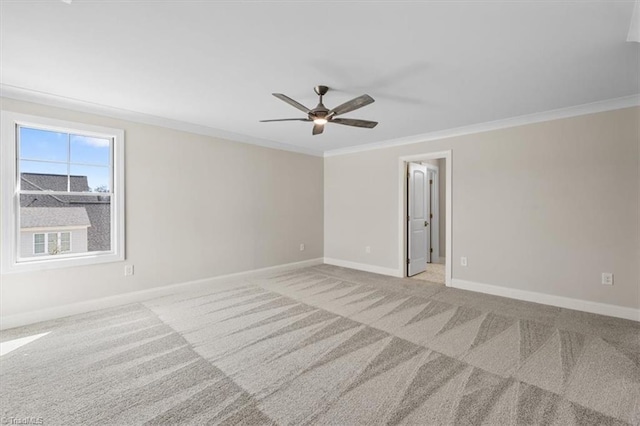 carpeted spare room with ceiling fan, crown molding, and baseboards