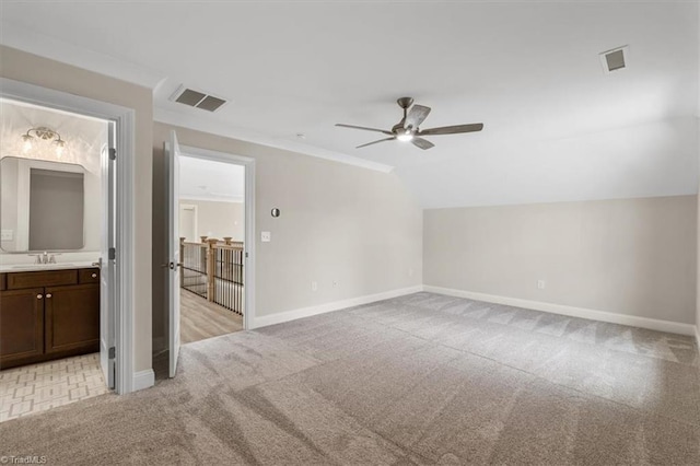 interior space featuring baseboards, visible vents, lofted ceiling, crown molding, and light colored carpet