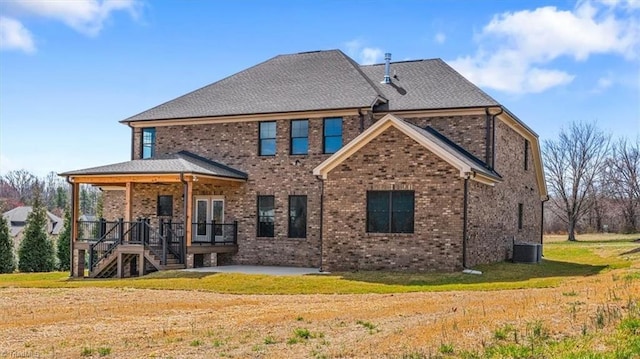 rear view of property with central air condition unit, brick siding, a lawn, and a patio area