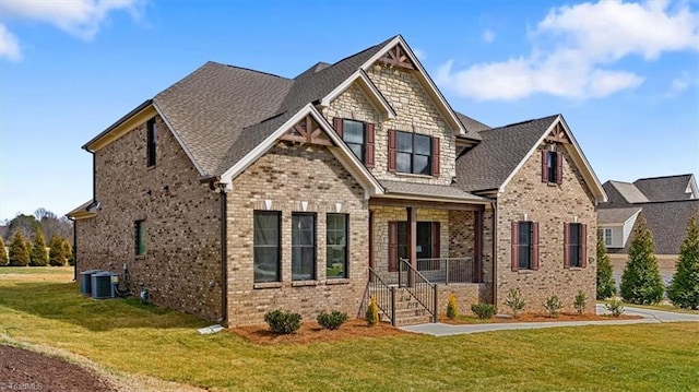 craftsman house with brick siding, a front yard, and a shingled roof