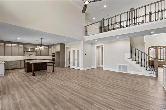 living room featuring stairway, baseboards, visible vents, and light wood-type flooring