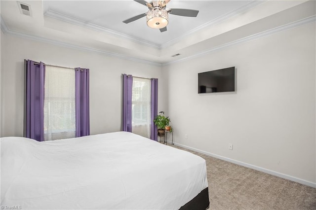 bedroom featuring a raised ceiling, multiple windows, ceiling fan, and light colored carpet