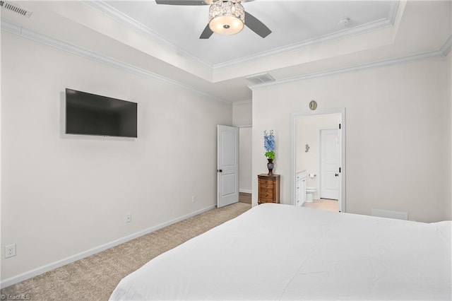 bedroom featuring a raised ceiling, ceiling fan, light colored carpet, and ensuite bathroom