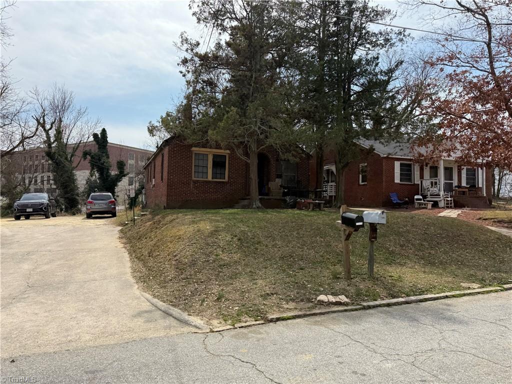 view of front of home with brick siding, covered porch, driveway, and a front lawn