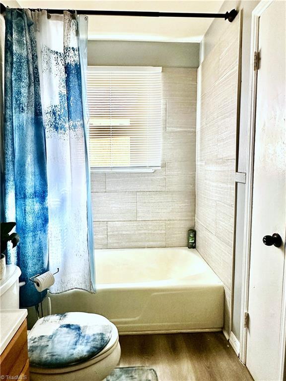 bathroom featuring vanity, shower / tub combo, toilet, and wood finished floors