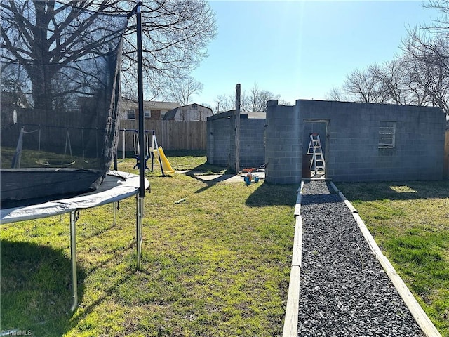 view of yard featuring a playground, a trampoline, and fence