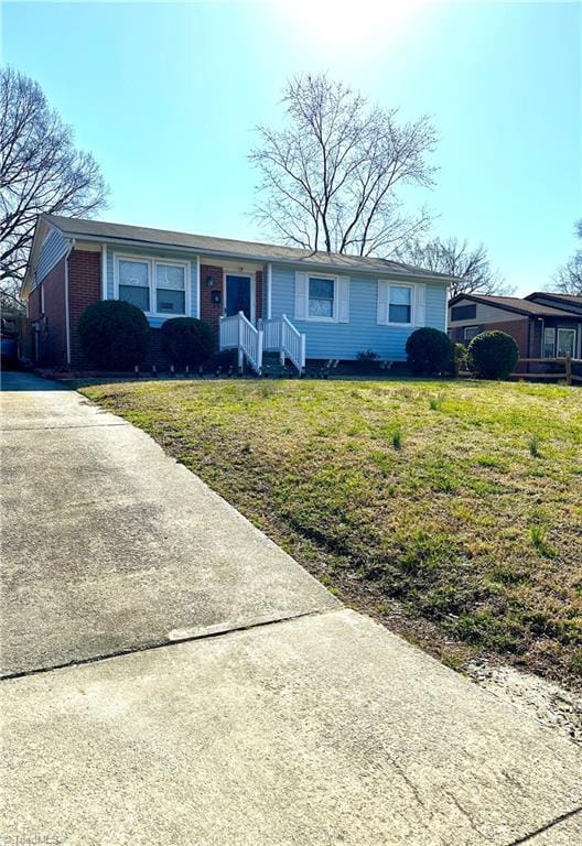 ranch-style house featuring a front lawn, brick siding, and driveway