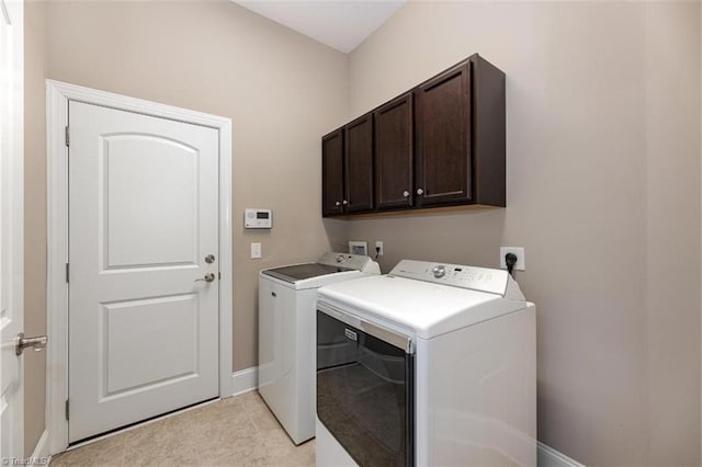 washroom featuring washing machine and clothes dryer, cabinet space, and baseboards