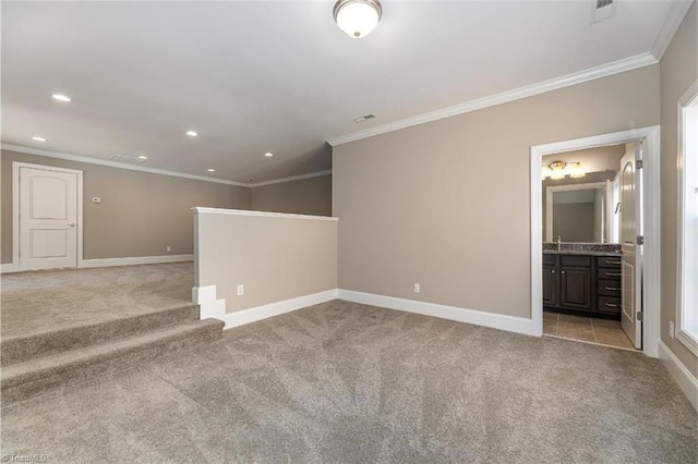 spare room with baseboards, crown molding, and light carpet