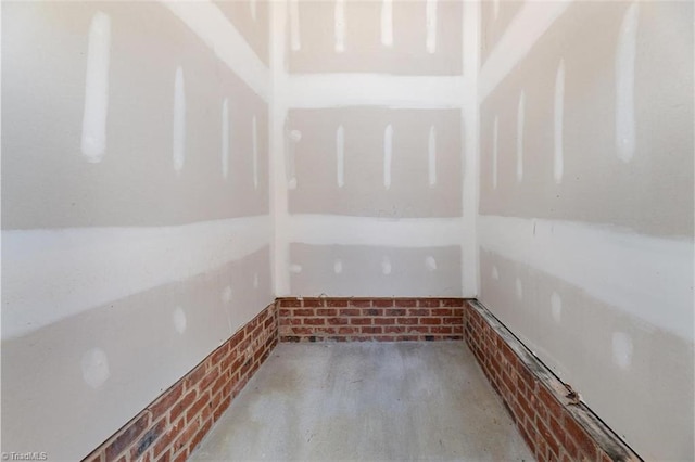 unfurnished room featuring brick wall