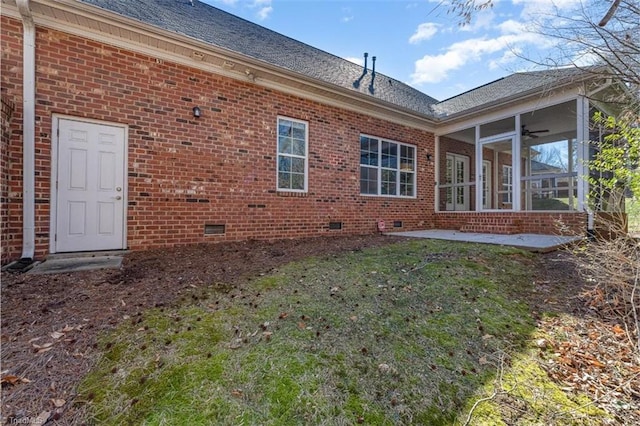 rear view of house with a shingled roof, crawl space, brick siding, a lawn, and a ceiling fan