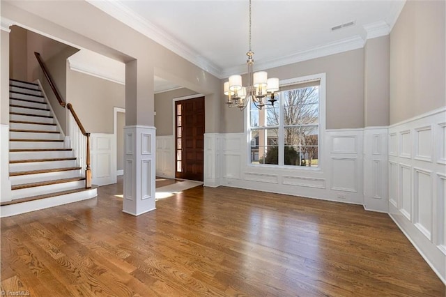 unfurnished dining area with visible vents, stairs, crown molding, a chandelier, and wood finished floors