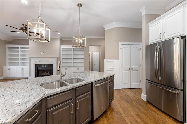 kitchen with dark brown cabinets, a sink, pendant lighting, appliances with stainless steel finishes, and white cabinets