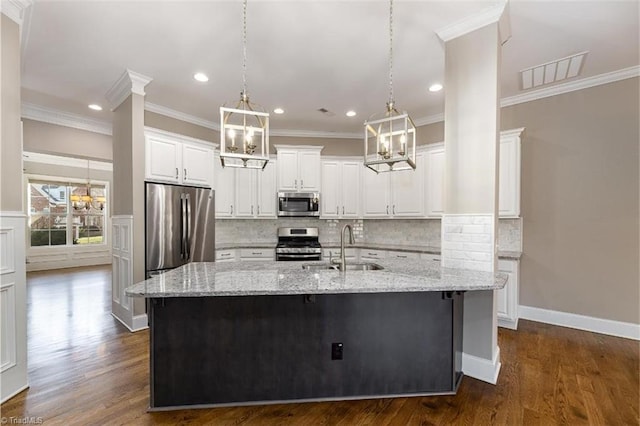 kitchen with stainless steel appliances, white cabinetry, a sink, and a kitchen island with sink