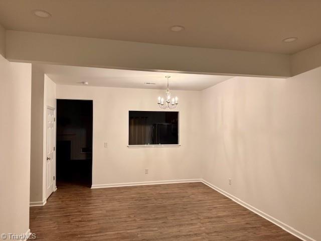 unfurnished room featuring a chandelier and dark wood-type flooring