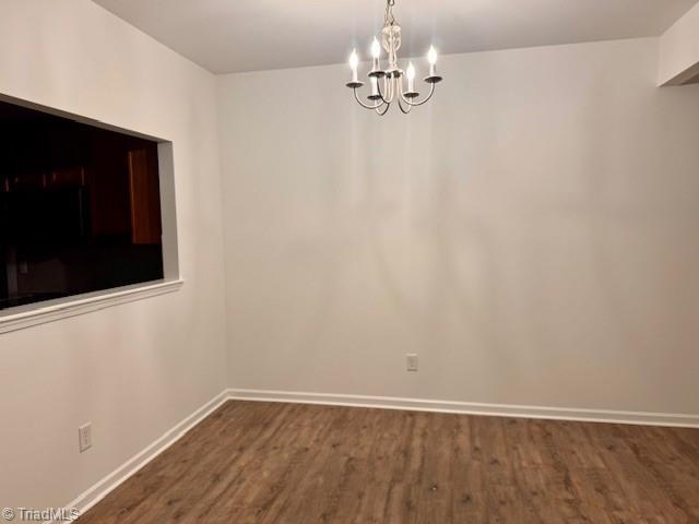 unfurnished dining area featuring dark wood-type flooring and a chandelier