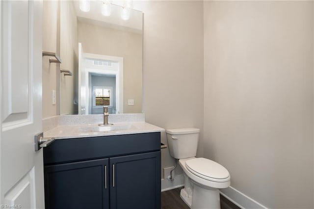 bathroom with hardwood / wood-style flooring, large vanity, and toilet