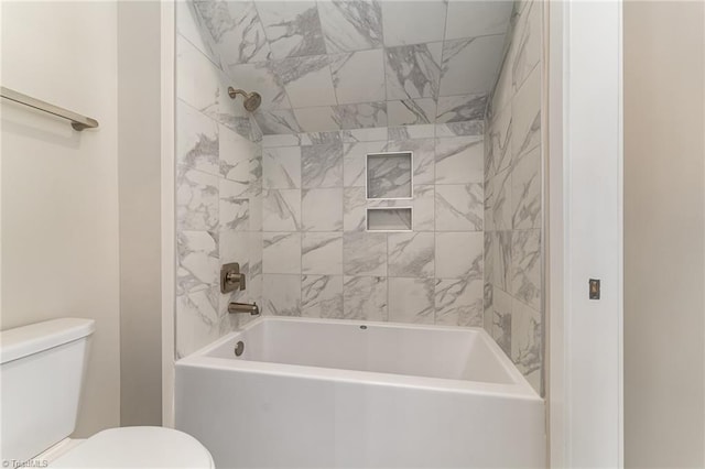 bathroom featuring tiled shower / bath combo and toilet