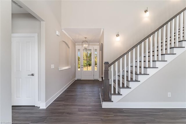 entrance foyer with a notable chandelier, crown molding, and dark hardwood / wood-style flooring