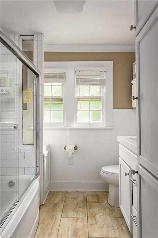 609 W Lexington Ave, High Point, NC 27262 - bathroom featuring vanity, crown molding, enclosed tub / shower combo, and a wainscoted wall