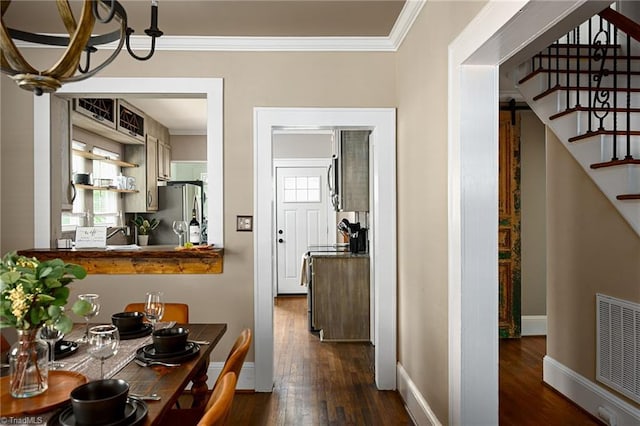 609 W Lexington Ave, High Point, NC 27262 - dining space with ornamental molding, dark wood finished floors, stairs, and a chandelier