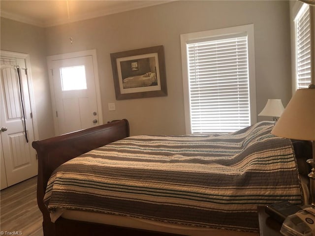 bedroom with ornamental molding and wood finished floors