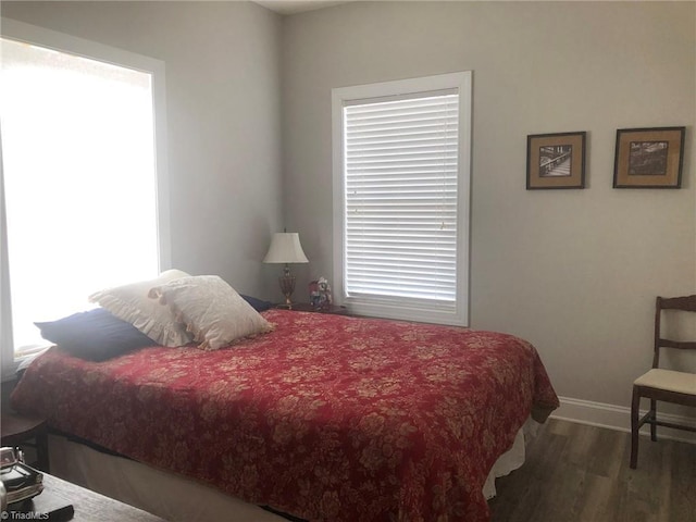 bedroom featuring multiple windows, baseboards, and wood finished floors