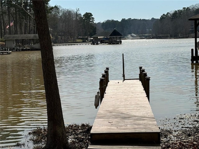 view of dock with a water view and a forest view