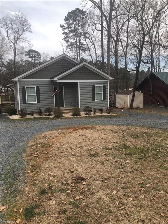 view of front of property featuring an outbuilding, a shed, a porch, and gravel driveway