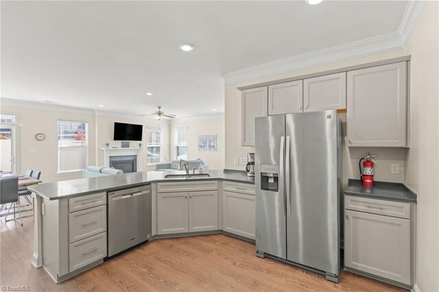 kitchen with appliances with stainless steel finishes, ornamental molding, light wood-type flooring, and gray cabinets