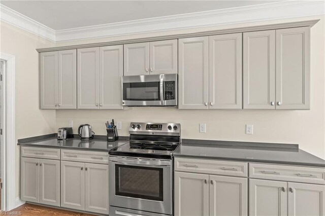 kitchen featuring crown molding, gray cabinetry, stainless steel appliances, and wood-type flooring