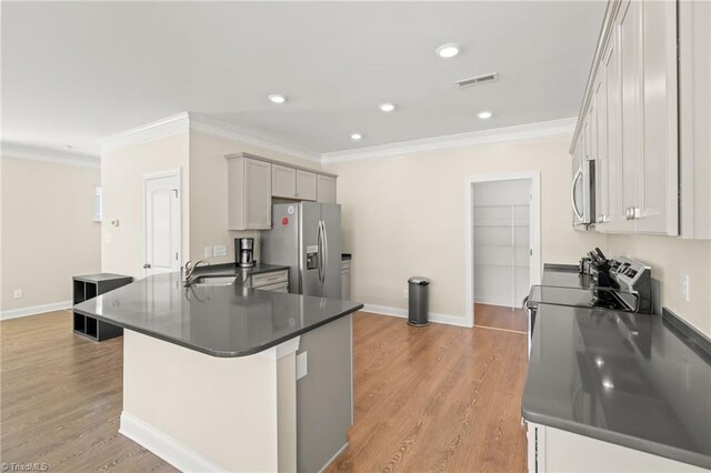 kitchen featuring appliances with stainless steel finishes, sink, a kitchen bar, crown molding, and light hardwood / wood-style flooring