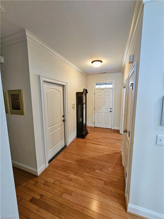 hallway featuring crown molding and light hardwood / wood-style flooring