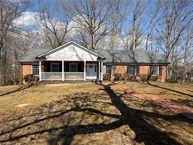 greek revival inspired property featuring a porch and brick siding