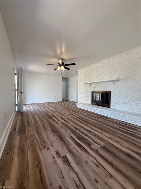 unfurnished living room with a glass covered fireplace, ceiling fan, baseboards, and wood finished floors