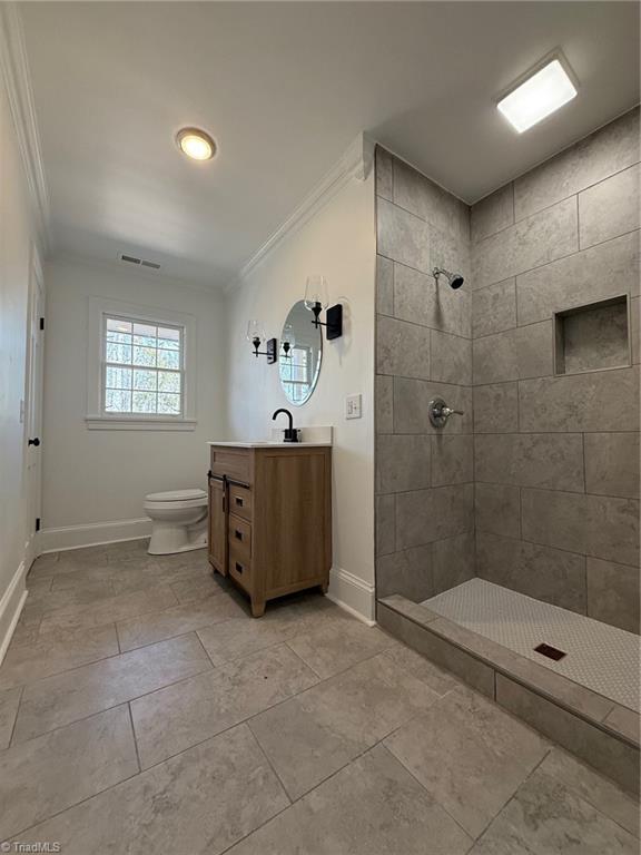 bathroom with ornamental molding, visible vents, a tile shower, and toilet