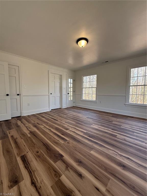 interior space featuring crown molding, dark wood-type flooring, and baseboards