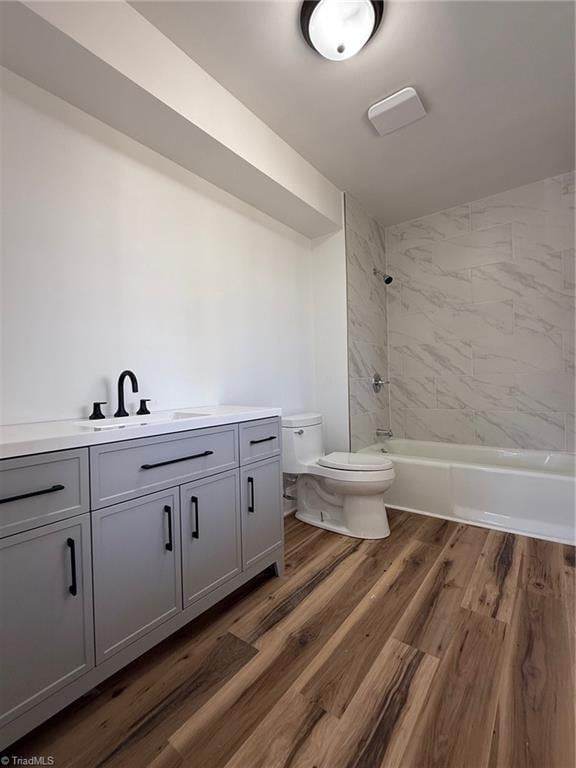 bathroom featuring washtub / shower combination, vanity, toilet, and wood finished floors