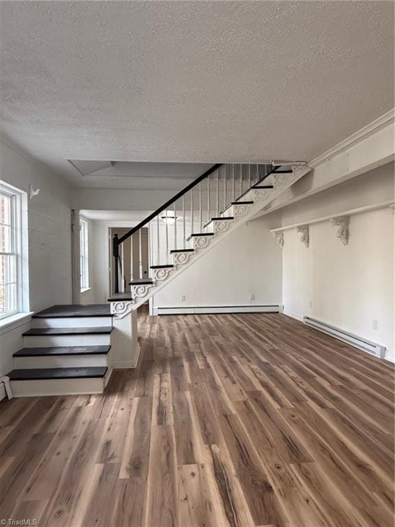 interior space featuring a textured ceiling, a baseboard radiator, stairs, and wood finished floors