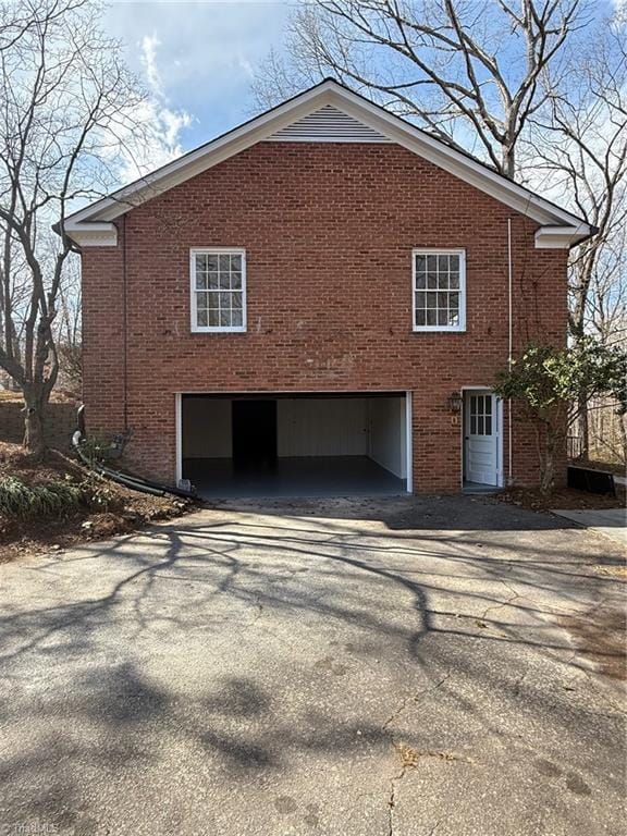 view of home's exterior with aphalt driveway, brick siding, and an attached garage