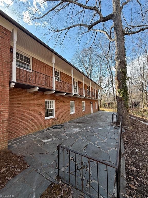 exterior space with brick siding and a balcony