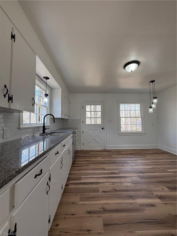 kitchen featuring plenty of natural light, white cabinetry, a sink, and wood finished floors