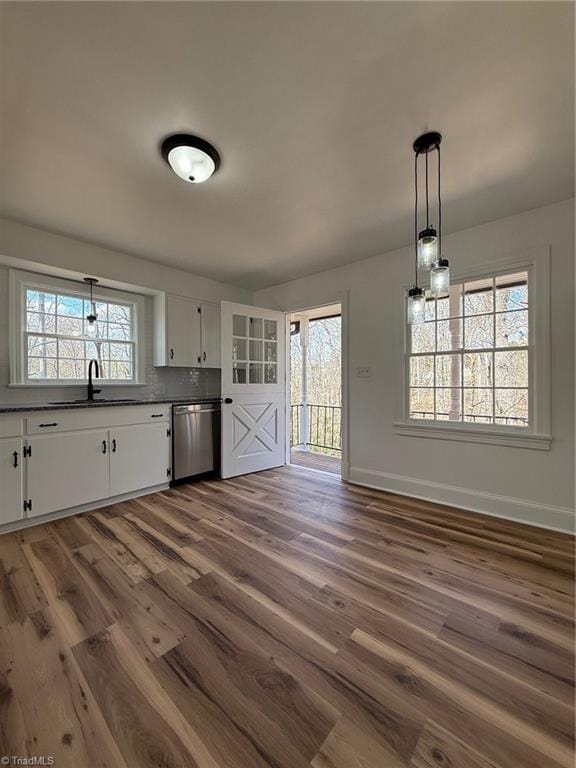 unfurnished dining area featuring dark wood-type flooring, a sink, and baseboards